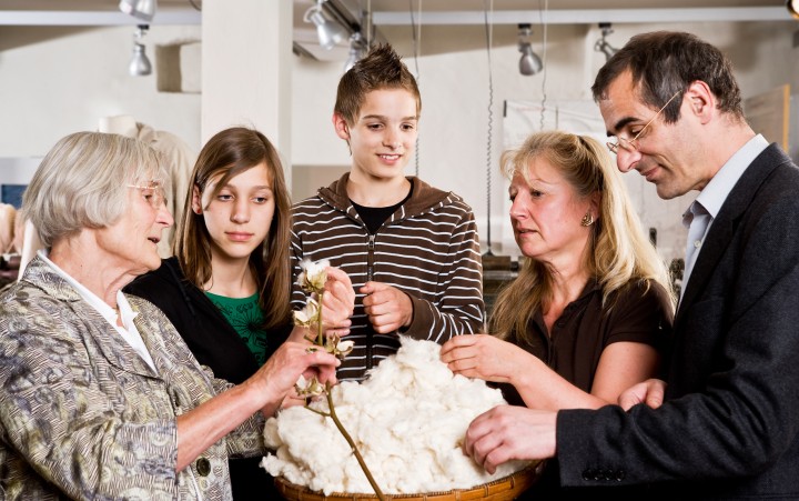 Family looks at raw cotton in a basket