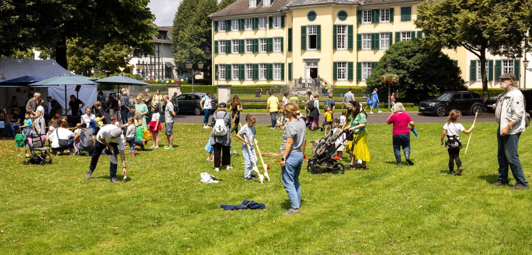 Viele Menschen auf einer Wiese vor dem Herrenhaus der Textilfabrik Cromford.