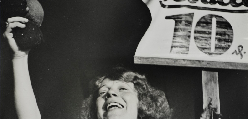 Schwarz Weiß Bild mit Plakat im Hintergrund. Frau mit ausgestrecktem Arm 