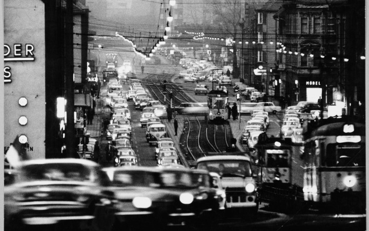 Schwarz-weiß-Fotografie einer Straßenszene mit Autos und Straßenbahnen