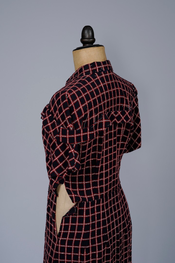 Ansicht des rot-schwarz karierten Damenkleids von schräg hinten, man erkennt eine offene Seitennaht