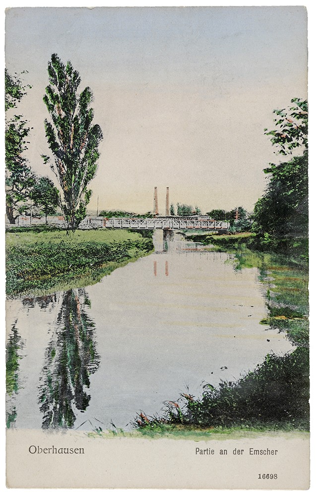 Postkarte zeigt einen ruhigen Fluss, in dessen Oberfläche sich die darum befindlichen Wiesen und Bäume spiegeln