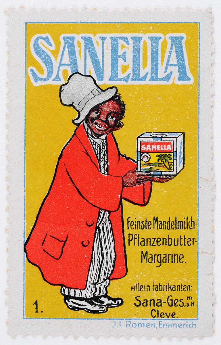 Reklamemarke von Sanella auf der eine Schwarze Person in übergroßem Anzug und mit Hut zu sehen ist, die eine packung Margarine in der Hand hält und in Richtung der Betrachter*innen schaut