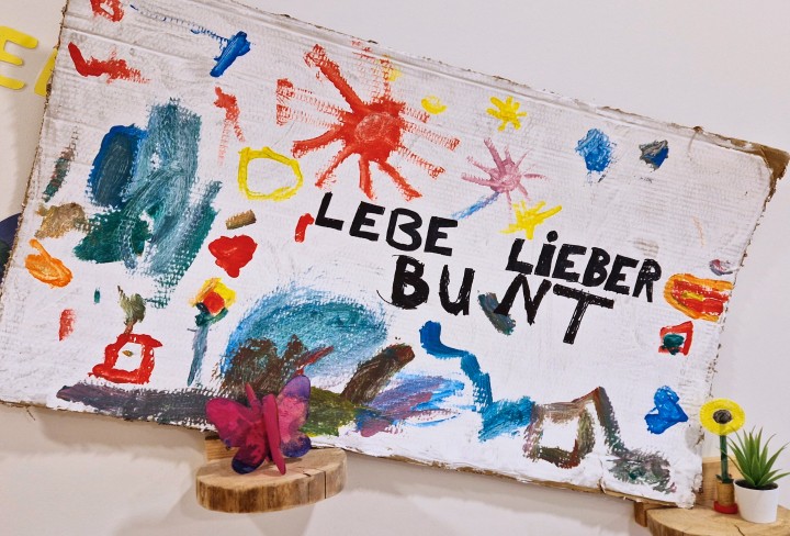 Ein von Kindern gemaltes Plakat auf dem geschrieben steht: "Lebe Lieber Bunt".