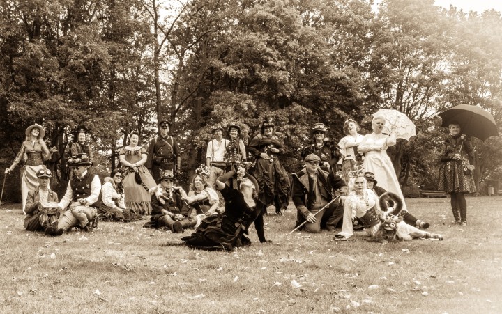 Fotografie in Sepia von posierenden Steampunks auf einer Wiese