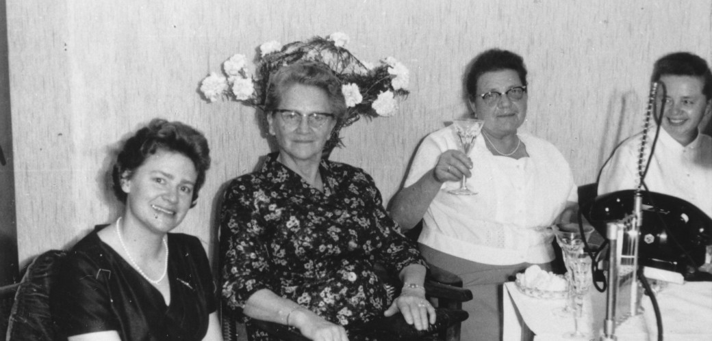 Historisches Bild von vier Frauen, eine von ihnen trinkt Sekt.