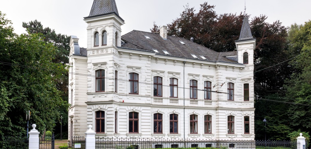 Herrenhaus mit Vorgarten und Mauer an einer Straße