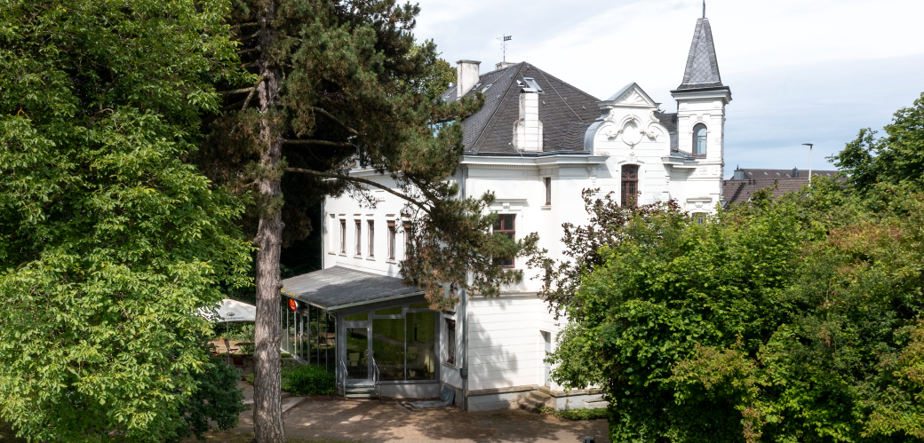 Herrenhaus mit Vorgarten und Mauer an einer Straße