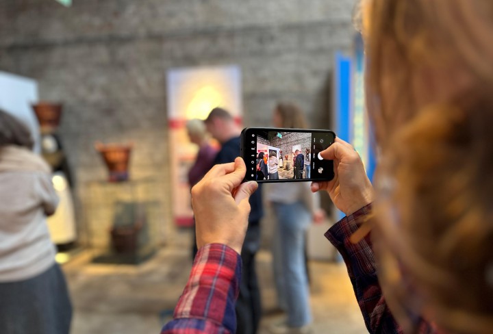 Eine Person die mit dem Handy in einer Ausstellung Fotos macht