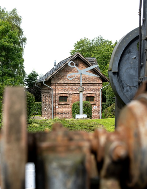 Außenansicht eines roten Backsteingebäudes mit einer Scherenstatue davor