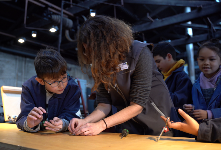 Kinder werkeln mit Museumspädagogin an einem Tisch