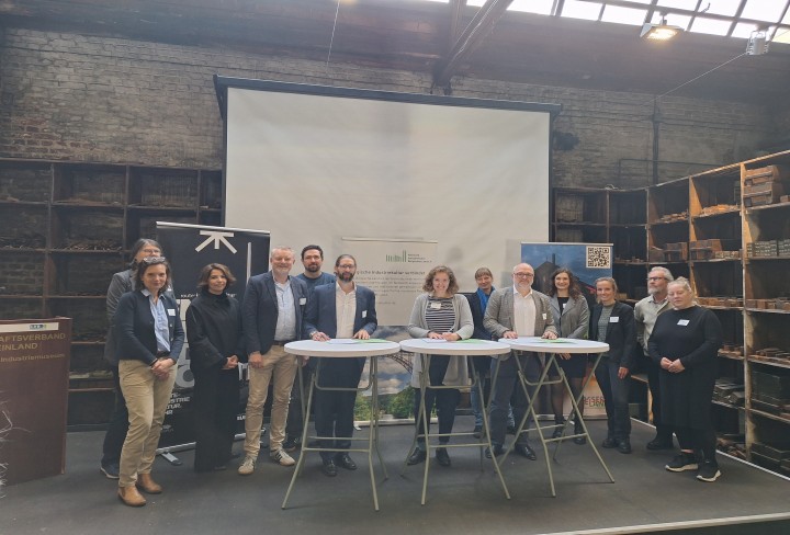 mehrere Personen posieren auf einer BÃ¼hne hinter Stehtischen