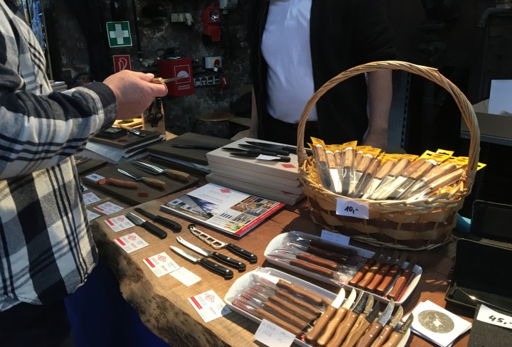 Verkaufsstand mit auf einem Tisch ausgebreiteten Messern und vielen kleinen Messern in einem Korb