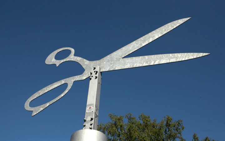 Large metal scissors against a blue sky