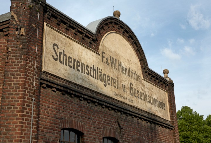 Sommerliche Außenansicht der historischen Eckfassade der Gesenkschmiede Hendrichs