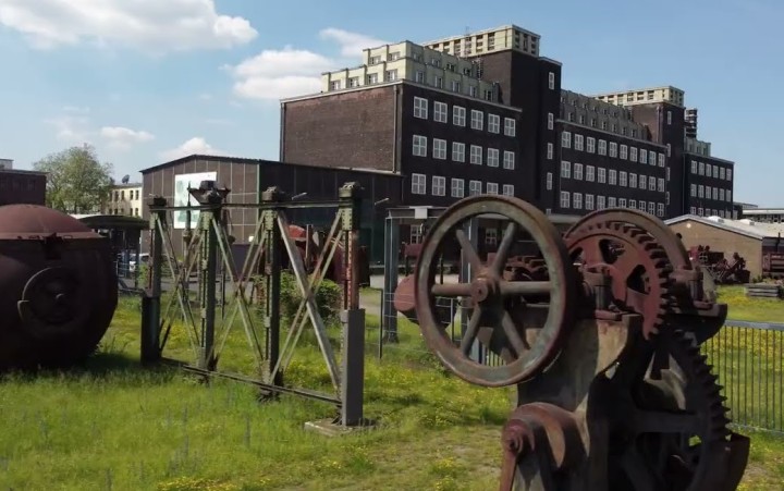 historische Maschinenteile vor dem Peter-Behrens-Bau