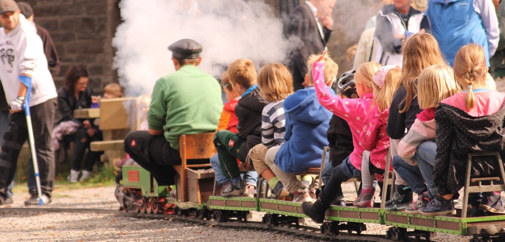 Kinder die eine Fahrt auf der kleinen Dampfeisenbahn drehen.