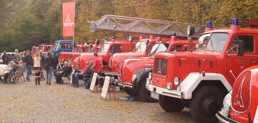 Historische Fahrzeuge der Feuerwehr stehen in einer Reihe.