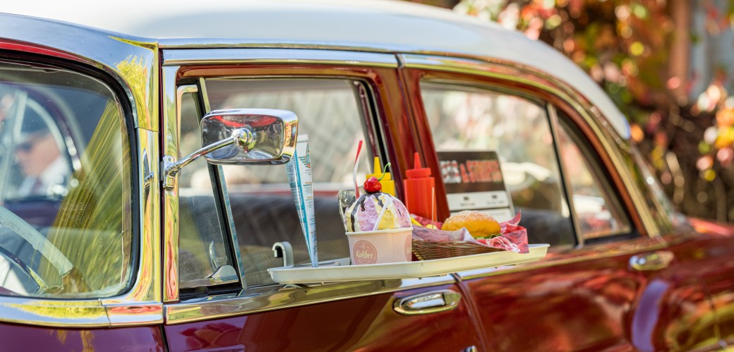 Tablett mit Eis, Soßenspendern und Snacks hängt an einem Oldtimer-Fenster