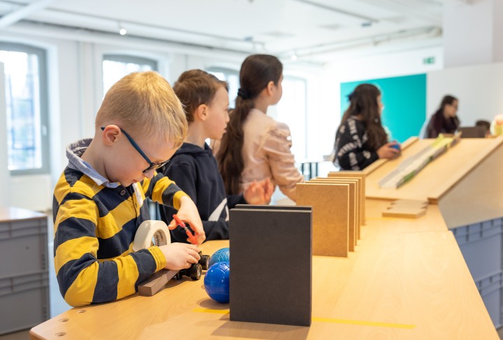 Kinder bauen an einer Kettenreaktion, Junge im Vordergrund