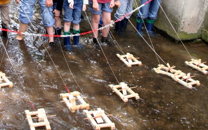 Kinder lassen kleine Boote in einen Bach