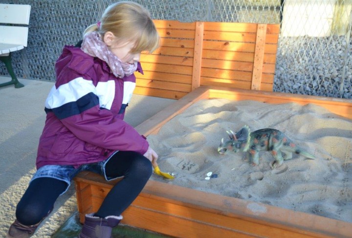 Ein Mädchen sitzt an einem Sandkasten