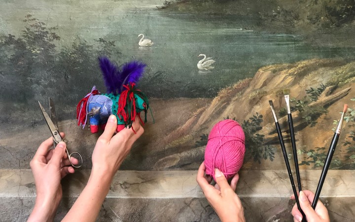Kinderhände halten Wolle und Pinsel vor ein Gemälde