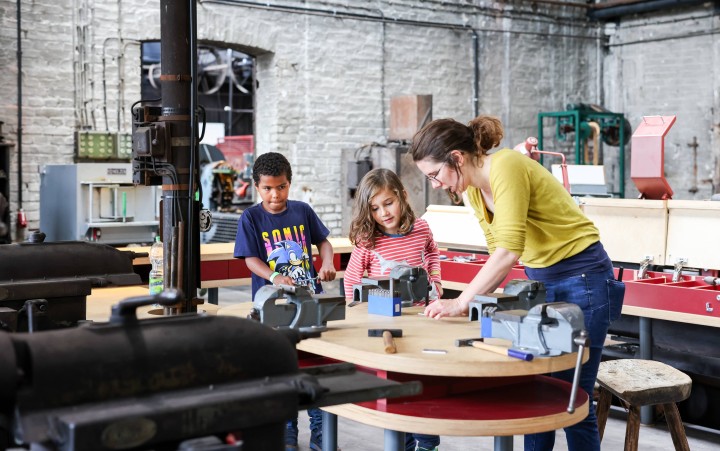 Kinder basteln mit Museumsmitarbeiterin an einem Tisch