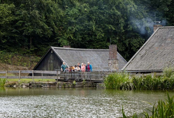 Blick auf einen See, dahinter eine Haus mit einem Holzsteg auf den Besucher stehen