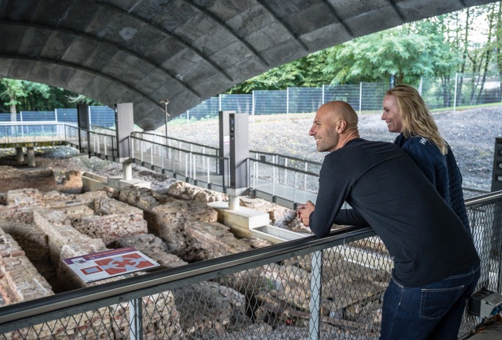 Ein Mann und eine Frau schauen in einer Ausgrabungsstätte auf die Ausgrabunbgssteine