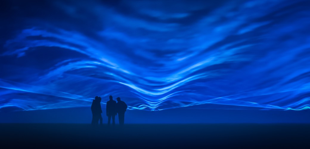 Vier Menschen stehen in einer großen blauen Lichtprojektion