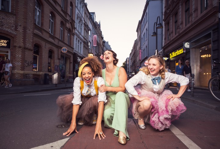 Drei Frau knien lachend auf einer Straße