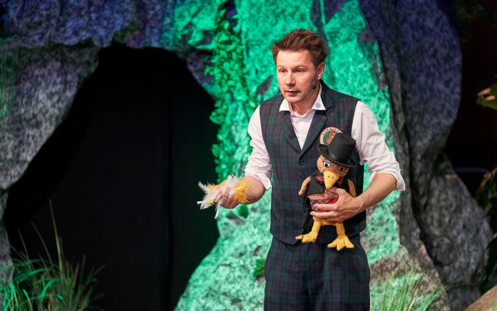 Mann mit Puppe in der Hand auf einer Bühne