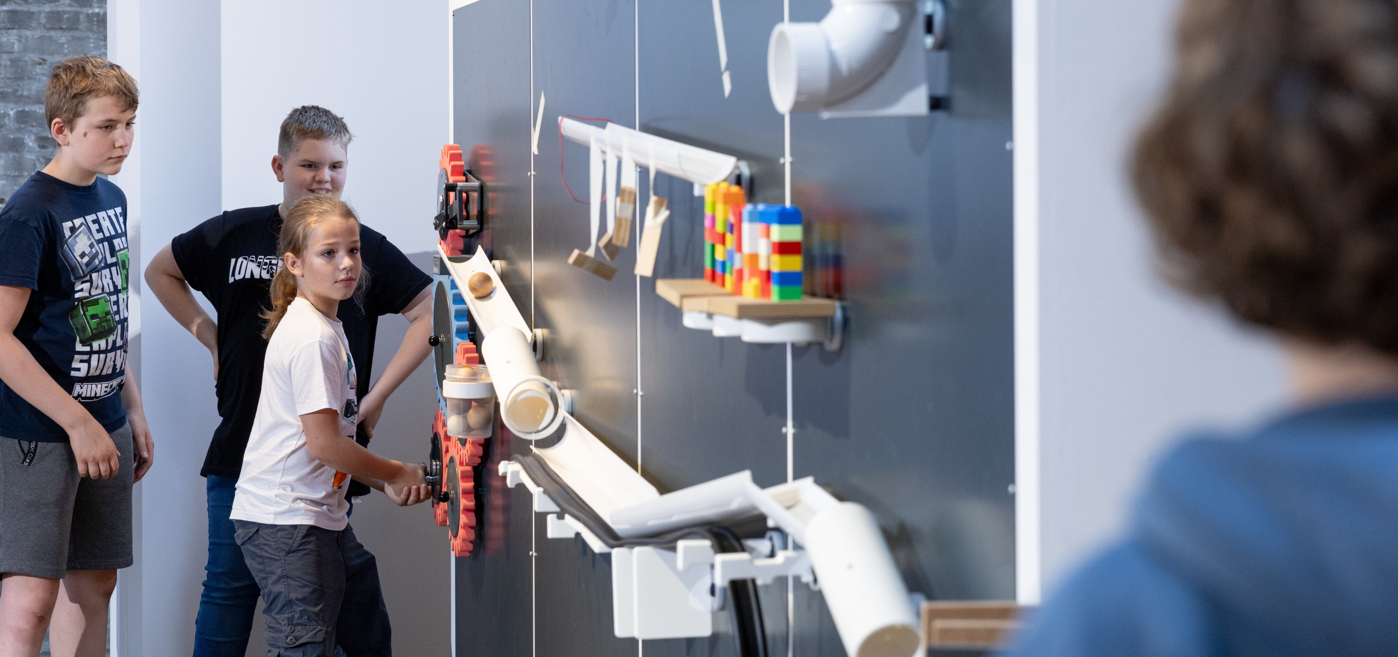 Kinder betätigen eine an der Wand aufgebaute Kettenreaktion