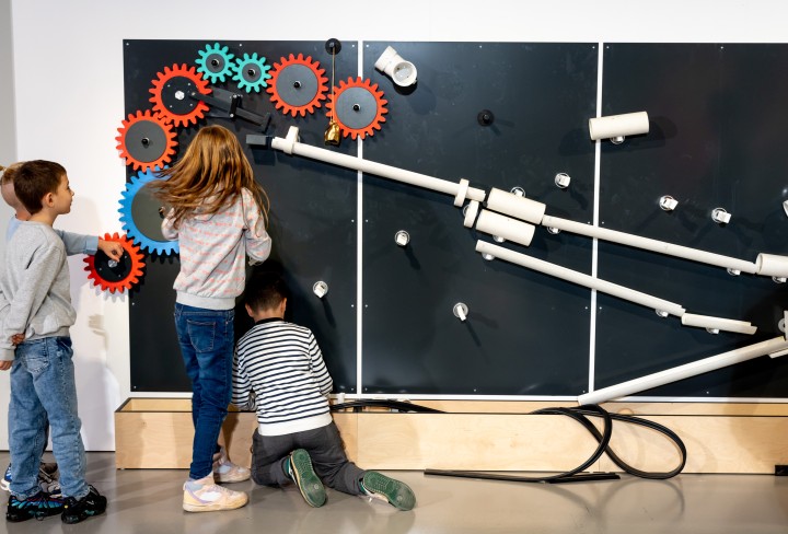 Kinder bauen bunte ZahnrÃ¤der an eine Wand
