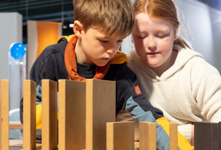 Ein Mädchen und ein Junge mit großen Dominosteinen aus Holz