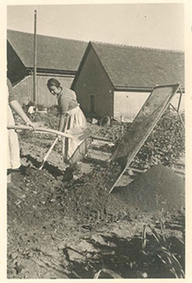 Ein Schwarzweißfoto zeigt zwei Frauen, die Komposterde sieben.