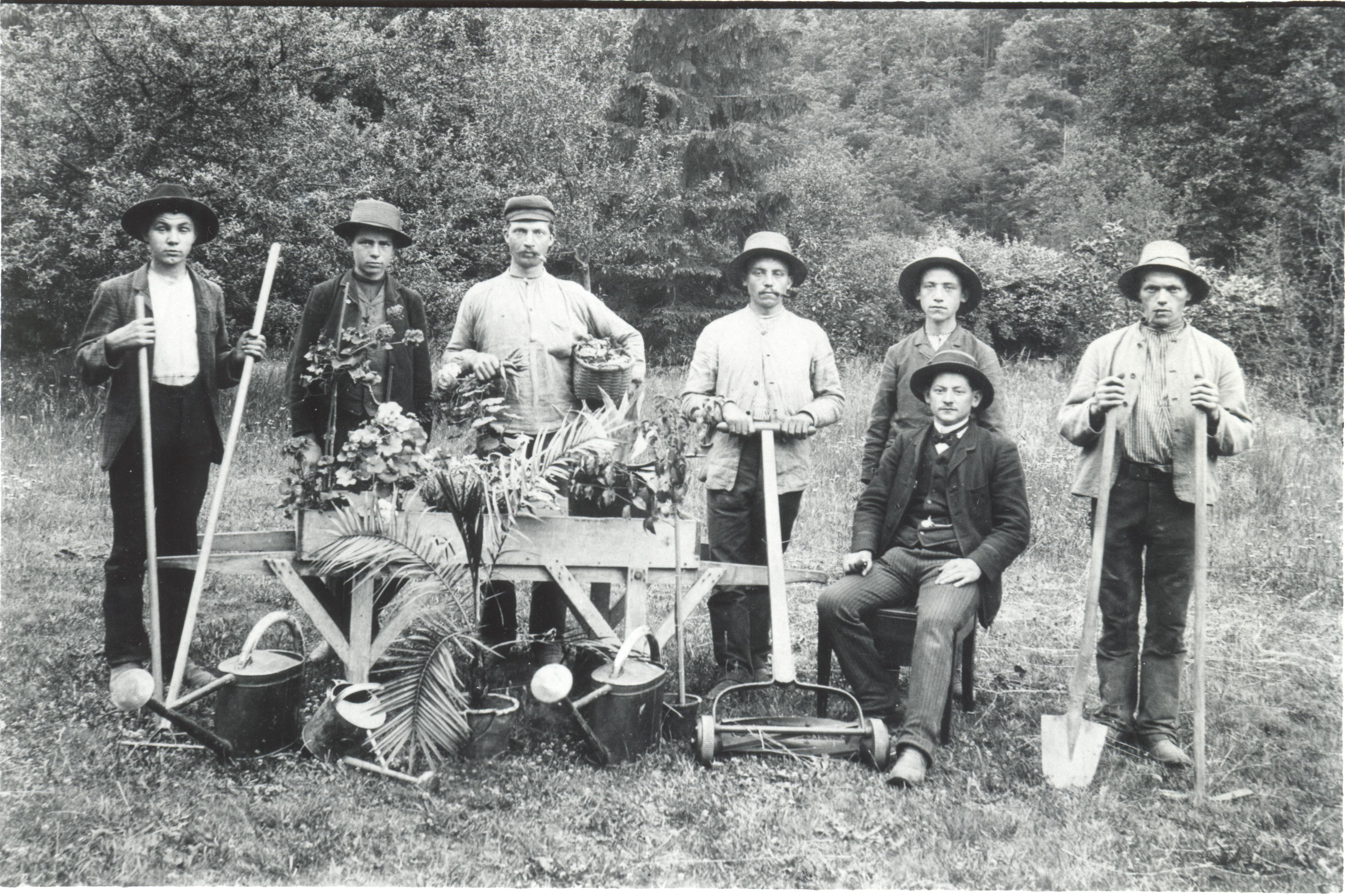 Historisches Schwarzweiß-Foto einer Gruppe Männer mit Gartengeräten